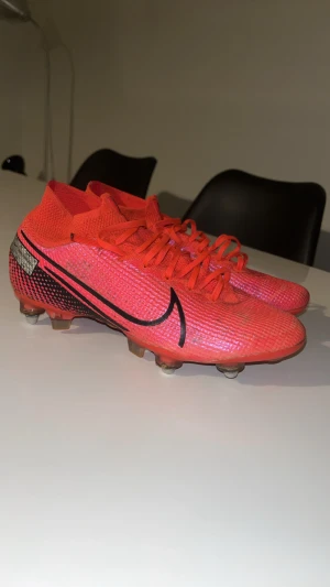 Nike Mercurial Superfly – Röd - Säljer ett par Nike Mercurial Superfly fotbollsskor i röd/svart färg. Skorna är lätta, bekväma och designade för maximal fart. Ovandelen är i flexibelt Flyknit-material och FG-sulans dobbar ger bra grepp på naturgräs. De är begagnade men i fint skick, utan större skador — bara normala användningsspår.