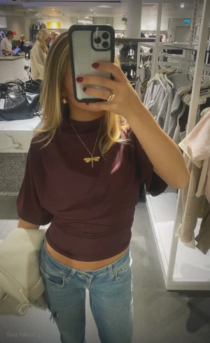 Vinröd polotröja med kort ärm - Snygg vinröd polotröja med korta ärmar och en hög krage. Tröjan har en stilren och enkel design med lätt drapering vid axlarna. Perfekt för dig som gillar minimalistiska plagg med en twist. Materialet känns mjukt och har ett lätt stretch.