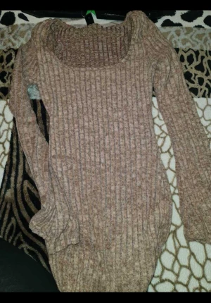 Ribbad beige stickad klänning - Superfin ribbad stickad klänning i beige ton med lång ärm och rundad urringning. Modellen är tight och kort, perfekt för dig som gillar en figurnära look. Materialet är mjukt och stretchigt, vilket gör den både bekväm och snygg.