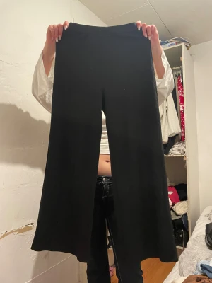 Svarta ribbade wide byxor i storlek S ifrån Shein  - Svarta ribbade byxor med breda ben och elastisk midja. Materialet är mjukt och stretchigt, perfekt för en chill och avslappnad look. Passar dig som gillar loose fit och vill ha något bekvämt men ändå stilrent.