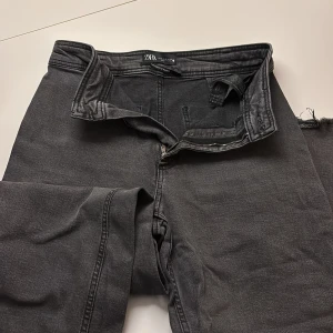 Svarta straight jeans från Zara - Snygga svarta jeans från Zara i modellen The Marine Straight. Jeansen har rak passform, klassisk femficksdesign och dragkedja i gylfen. Materialet är mjukt och bekvämt, perfekt för dig som gillar en clean och stilren look.