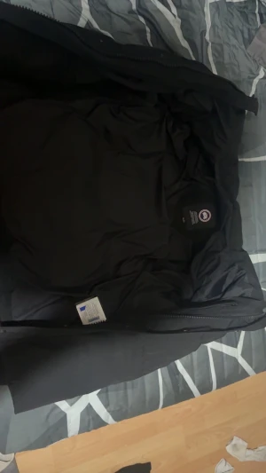 Svart dunjacka från Canada Goose - Säljer en svart dunjacka från Canada Goose med klassisk patch på ärmen. Jackan är tjockt vadderad, har hög krage och dragkedja framtill. Perfekt för kalla dagar och riktigt snygg  streetstil. en skadda som inte syns. Och luva och päls finns