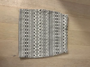 Svartvit mönstrad kortkjol - Säljer en svartvit kortkjol med grafiskt mönster och tajt passform. Kjolen har elastisk midja och är perfekt för dig som gillar en stilren men ändå iögonfallande look. Materialet känns mjukt och stretchigt, vilket gör den bekväm att bära hela dagen.