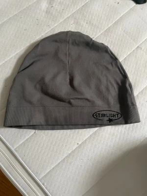 Starlight mössa - Snygg grå mössa från Starlight med enkel design och logga framtill. Mjuk och skön passform, perfekt för att hålla värmen när det är kyligt ute. Tillverkad i bomullsmaterial som känns bekvämt mot huden.