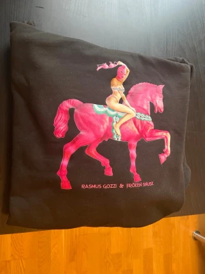 Fröken Snusk Dalahäst Hoddie  - Säljer en Fröken snusk Dalahäst Hoddie i fint skick. Storlek XL men skulle nog säga att den mer är åt M hållet!