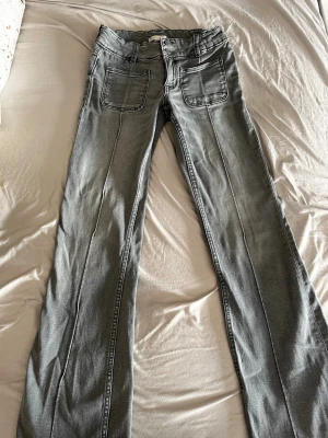 Grå jeansbyxor från Gina Tricot - Snygga grå jeansbyxor från Gina Tricot i storlek 158. Modellen har vida ben (bootcut), stora framfickor och dubbla knappar i midjan. Justerbar midja med resår på insidan för extra komfort. Perfekt för dig som gillar en enkel och cool look. Köpt för 500kr