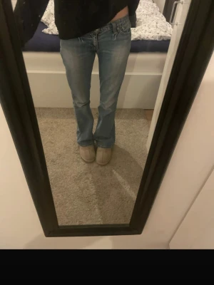 Levis Low bootcut jeans ljusblå - Midjemått: 38cm Innerbenslängd: 79 cm Säljer ett par klassiska Levis jeans i ljusblå tvätt med bootcut-snitt och låg midja. Jeansen har fem fickor, dragkedja och knapp framtill samt Levis-logga på bakfickan. Materialet är slitstarkt jeans och passformen är loose med lite utsvängda ben. Obs lite slitna längst ner samt på lappen där bak se bilderna. 