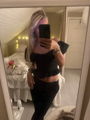 Svart offshoulder topp med volang - Säljer en svart offshoulder topp med breda puffiga ärmar och med en volangkant nedtill. 