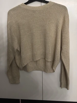 Beige stickad tröja från H&M Divided - Säljer en beige stickad tröja från H&M Divided i storlek S. Tröjan har en loose passform, ribbad rund hals och ribbade muddar vid ärmslut och nederkant. Perfekt för lager-på-lager och chill dagar. Enkel och stilren design som är lätt att matcha.