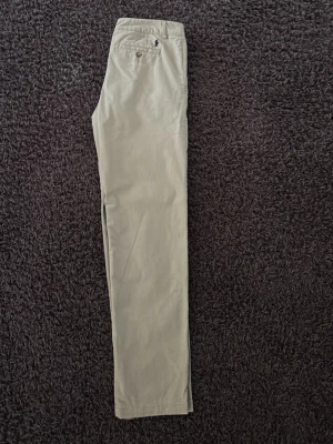 Beiga chinos från Polo Ralph Lauren - Säljer ett par klassiska beiga chinos från Polo Ralph Lauren. Byxorna har normal passform, raka ben och bälteshällor. Tillverkade i mjuk bomull med knapp och dragkedja fram. Perfekta till en clean och stilren look. Nypris 1499. Innerbenlänged är 72 cm 