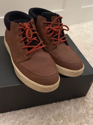 Bruna Etnies Crestone MTW sneakers - Säljer ett par bruna Etnies Crestone MTW sneakers med slitstark Michelin-sula. Skorna har rödsvarta snören, svart vadderad kant och ovandel i skinn och syntet. Perfekta för dig som vill ha streetstil med robust känsla.