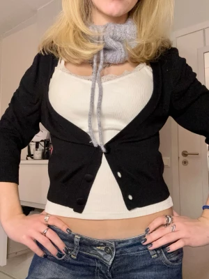 Svart kofta med knappar, croppad - Svart croppad kofta med tre knappar framtill, och rynk detaljer vid axlarna. Koftan har lite kortare ärmar och är gjord i ett mjukt stickat material. Storlek S🥰