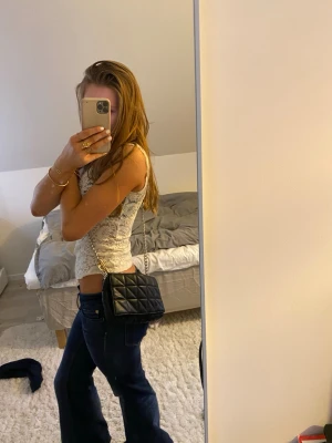 Svart quiltad axelväska med kedja - Säljer en svart axelväska i quiltad design med snygg kedjerem i silverfärg. Väskan är rektangulär och har ett stilrent uttryck som passar till många outfits. Materialet är skinnimitation och insidan har ett fack för småsaker. Perfekt storlek för det viktigaste.