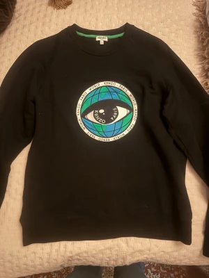 Äkta Svart Kenzo sweatshirt med tryck - Svart sweatshirt från Kenzo i storlek S med ett stort färgglatt tryck på bröstet som föreställer ett öga och jordglob. 