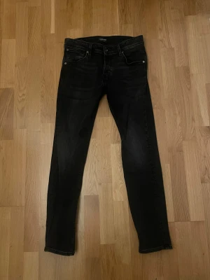Jack and jones, slim glenn - Svarta jeans från Jack & Jones, modell Slim/Glenn. Snyggt smal passform med klassiska fem fickor och bälteshällor. Jeansen har en mörk tvätt och är tillverkade i stretchigt denim för extra komfort. Perfekt för dig som gillar en stilren och modern look.
