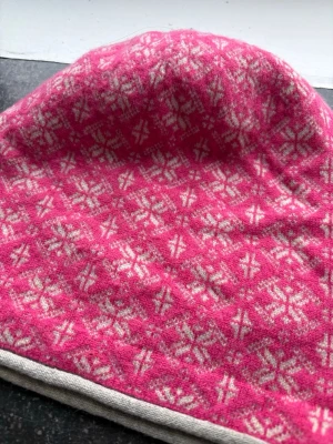 Rosa stickad mössa från Odd Molly - Säljer en rosa stickad mössa från Odd Molly med vitt mönster. Mössan  har en mjuk känsla och är tillverkad i ullblandning med 80% ull och 20% nylon. Den har ett klassiskt mönster och ljusgrå kant nedtill. Perfekt för dig som gillar färg och mönster.