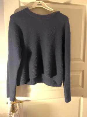 Mörkblå stickad tröja med loose fit - Mysig mörkblå stickad tröja med rund halsringning och långa ärmar. Tröjan har en loose fit och ribbade muddar vid ärmslut och nederkant. Perfekt till chill outfits med jeans, kjol, shorts eller bara mjukisbyxor