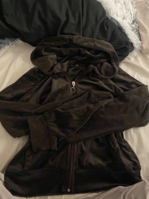 brun velour hoodie med dragkedja - Mjuk och skön svart hoodie i velour med huva och dragkedja framtill. Tröjan har långa ärmar, snörning i huvan och en snygg ringdetalj på dragkedjan. Perfekt för chill dagar eller när du vill vara extra bekväm.