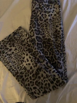 Leopardmönstrade jeansbyxor - Säljer ett par riktigt snygga jeansbyxor med leopardmönster i svart och grått. Byxorna har klassisk femficksdesign och normal passform. Perfekta för dig som vill sticka ut och addera lite edge till din outfit. Storlek 27 vet inte riktigt vad det är i bokstavs storlekar men passar mig som vanligtvis har s i byxor.