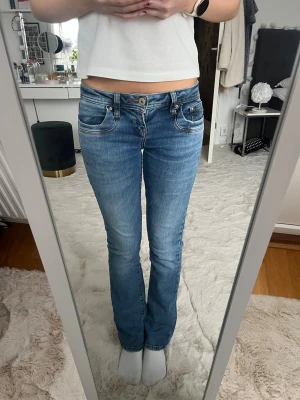 Blå lågmidjade bootcut jeans från LTB - Säljer ett par blå lågmidjade bootcut jeans från LTB i storlek 24/30 (24-midjan, 30-längd). Jag har själv inte använt de mycket men köpte de på Plick för ett tag sedan så de är använda sen innan. Det finns ett hål mellan bena på jeansen som man kan se på sista bilden, det är inte stort och syns inte på mig när jag har på mig de💕💕