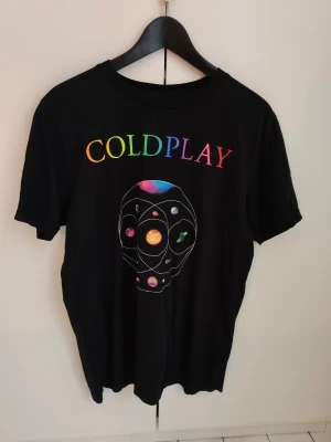Coldplay Music of the Spheres t-shirt M - Säljer en svart Coldplay Music of the Spheres t-shirt i storlek M. Trycket fram har färgglad Coldplay-text och ett coolt planetsystem, medan baksidan visar turnédatum i regnbågsfärger. Köpt på deras kosert i Göteborg 2023, endast använd ca 3 gånger - som ny! perfekt för dig som älskar bandmerch 