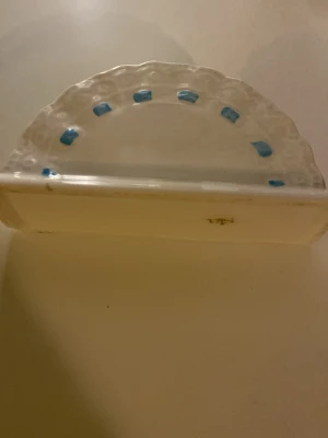 Vit keramik från Sia - Halvcirkelformad vit keramik från Sia med blå prickdetaljer längs kanten. Den har en klassisk och enkel design med lätt vågig kant och plats för förvaring. Perfekt för dig som gillar stilrena detaljer. Kan användas till caffefilter och papper, själv använde jag den till ansiktsmasker:)