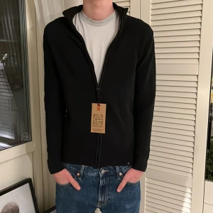 Svart kofta med dragkedja från INDICODE - Säljer en stilren svart kofta från INDICODE i storlek M. Koftan har hel dragkedja och är  i nyskick. 