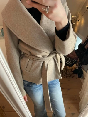 Beige omlottkappa från Vero Moda - Säljer en beige kappa från Vero Moda med skärp. OBS! Hänget är trasigt det man hänger upp kappan med!!❤️❤️