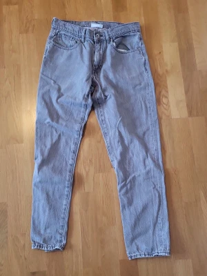 Gråa straight jeans i klassisk modell - Säljer ett par gråa jeans med rak passform och klassisk femficksdesign. Jeansen har normal midja och är tillverkade i jeansmaterial. Perfekta för dig som gillar en enkel och tidlös stil.