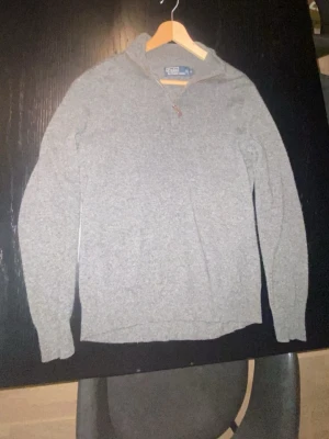 Grå halvzip tröja Polo Ralph Lauren - Säljer en stilren grå långärmad tröja från Polo Ralph Lauren. Tröjan har en klassisk half zip-dragkedja och hög krage. Perfekt till höst och vinter, i mjukt stickat material som håller dig varm. Enkel att matcha med jeans, köpt för runt 2500, denna är 100% Kashmir 