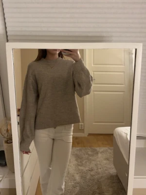 Beige stickad tröja från H&M - Mysig beige stickad tröja från H&M i storlek XS. Tröjan har en relaxed passform med långa ärmar och ribbade muddar vid hals och ärmslut. Perfekt för lager på lager under höst och vinter. Enkel att styla till både jeans och kjol.