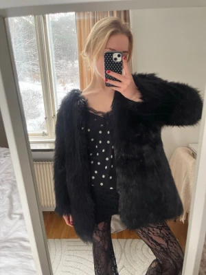 Svart pälsjacka  - Säljer en svart pälsjacka med lång ärm och klassisk rak passform. Jackan är fluffig och har en snygg, lite oversized look som ger en cool vibe. Perfekt för dig som vill sticka ut och hålla dig varm under kallare dagar.