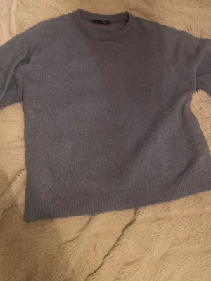 Ljusblå stickad tröja från 157 - Mysig ljusblå stickad tröja från Lager 157 i storlek M. Tröjan har rund halsringning och ribbade muddar vid ärmslut och nederkant. Perfekt för kyliga dagar och enkel att matcha med jeans eller kjol.