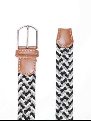 Flätat ”grisch” bälte - Svart/Grå & Vit - Snyggt och funktionellt flätat bälte från Montore, perfekt för både vardag och mer uppklädda outfits. Det elastiska materialet ger en bekväm passform och gör att bältet sitter bra hela dagen, oavsett tillfälle. Klassisk design med detaljer i konstläder och metallspänne som passar lika bra till jeans, chinos eller kostymbyxor. Bältet är justerbart utan fasta hål tack vare den flätade strukturen, vilket ger extra flexibilitet och komfort. Vid fler frågor, tveka inte att kontakta oss🤝✅