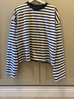 Randig långärmad t-shirt från Scuffers - Säljer en långärmad t-shirt från Scuffers i storlek S. Tröjan är vit med blåa horisontella ränder och har en cool gul SCFFRS-print på ryggen. Rund hals med blå kant och loose fit. Tillverkad i mjuk bomull, perfekt för dig som gillar streetwear och snygga prints. Plagget är i helt nytt skick och har aldrig använts.