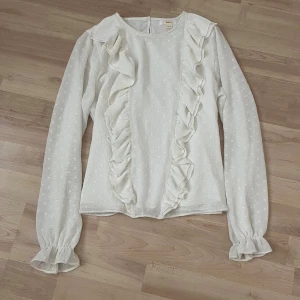 Volangblus  - Vit blus från Gina Tricot med volanger. Långärmad med lite puff vid ärmslutet och rund halsringning. Funkar som strl XS 