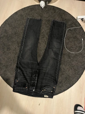 Levi's 501 svarta jeans W34 L30 - Svarta Levi's 501 jeans med klassisk rak passform och knappgylf. Jeansen har fem fickor, tydliga nitar och läderpatch bak i midjan. Materialet är robust denim i bomull och färgen är snyggt tvättad svart. Perfekta för en stilren och avslappnad look. Priset går att diskutera!
