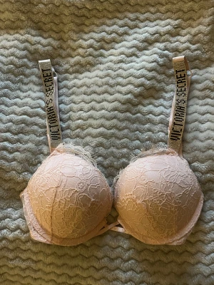 Rosa spets-bh från Victoria's Secret - BH från Victoria's Secret med push up. Axelband med glittriga stenar och texten 'Victoria's Secret'. I gott skick med har tecken på användning. Pris kan diskuteras.
