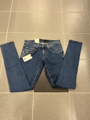 Blå slimmade jeans från Tiger of swedenW29 L32 - Säljer ett par klassiska blå slim jeans från T/J med smal passform och smala ben. Jeansen har fem fickor, snygga kontrastsömmar och läderpatch bak i midjan. Perfekta för dig som gillar en slimmad look.