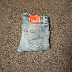 Jacob cohen jeans - Snygga ljusblå jeans från Jacob Cohen med röda detaljer och kontrastsömmar. Strl 32 riktigt bra skick 