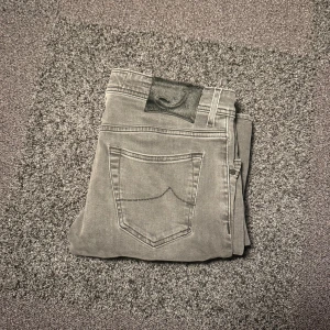 Jacob cohen jeans - Säljer ett par grå jeans från Jacob Cohen med klassisk femficksdesign och snyggt läderpatch bak i midjan. Storlek 32 mycket bra skick 