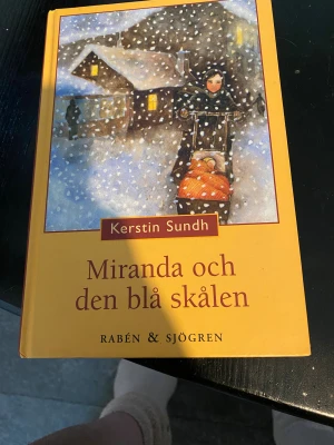 Miranda och den blå skålen - Följ Miranda i en vintrig småstad där drömmar, hemligheter och vardagsliv möts. Med kapitel som 'Dam i bil' och 'Jul i stugan' bjuder boken på spännande och känslosamma berättelser om familj, vänskap och mysteriet med den blå skålen. Perfekt för unga som gillar äventyr och känslor.
