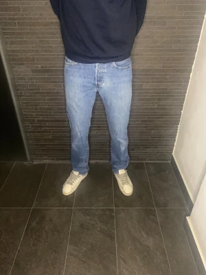 Levi's 501 ljusblå jeans  - Säljer ett par klassiska Levi's 501 jeans i ljusblå tvätt. Modellen har rak passform och normal midja, med fem fickor och knappgylf. Jeansen är tillverkade i slitstarkt bomullsdenim och har den ikoniska läderpatchen bak i midjan. W31 L34. Hör av dig vid frågor eller prisförslag!🤝