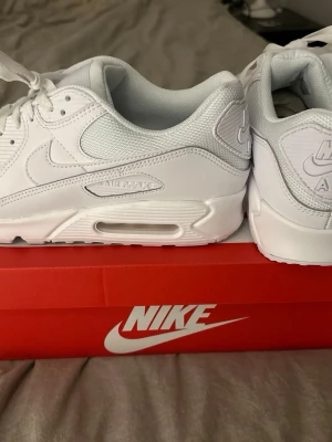 Nike Air Max 90 vit - Säljer ett par fräscha Nike Air Max 90 i helvitt. Säljer då jag köpte en för stor storlek. Detta är 45or. Helt nya och oanvända. Perfekta för dig som vill ha en clean och stilren sneaker med maxad komfort och streetkänsla. Köpt från Zalando ordinarie pris 1850kr