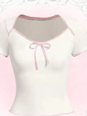 Vit blus med rosa rosett och kant Storlek M - Säljer en söt vit blus med ljusrosa kant och en liten rosett framtill. Blusen har korta ärmar och en mjuk, feminin design som passar perfekt till ljusa dagar. Materialet känns lätt och bekvämt mot huden.