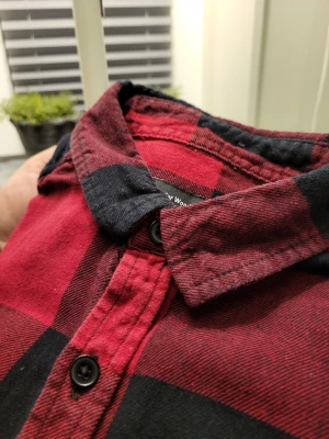 Röd och svart rutig skjorta Cedar Wood State - Säljer en röd och svart rutig skjorta från Cedar Wood State i storlek XS. Skjortan har klassisk krage, två bröstfickor och svarta knappar framtill samt vid ärmsluten. Tillverkad i mjuk bomull, perfekt för en avslappnad och cool look.