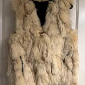 Beige fluffig pälsväst med quiltad insida - Säljer en beige pälsväst med fluffig look och quiltad svart insida. Storlek S , skriv vid fler frågor 