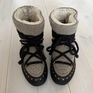 Inuikii curly vinterskor  - Säljer dessa superfina inuikii vinterskor. Använda men fortfarande mycket fina. Skinnet har slitits på baksidan och något på framsidan vid tåslutet. Några bitar på skornas baksida är missfärgade. Skicket syns tydligt på bilderna. 