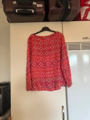 Odd molly topp - Säljer en otroligt vacker topp i en mörkare korall färg. Den har ett fint detaljerat mönster i orange, vitt och rosa.  Från märket Odd Molly. Storlek 2 som enligt deras storleksguide motsvarar en M. Mycket fint skick, jag hittar inga synliga anmärkningar eller defekter.