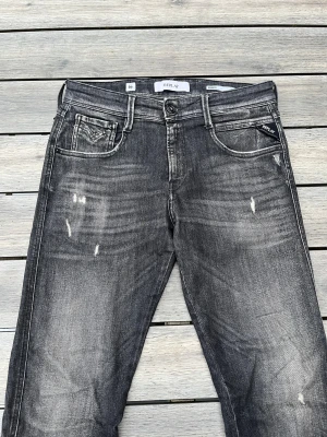 Replay jeans med slitningar  - Replay anbass i en fet modell med slitningar! Fint skick, inga defekter. Storlek 30/32. Kontakta mig för fler frågor och funderingar!